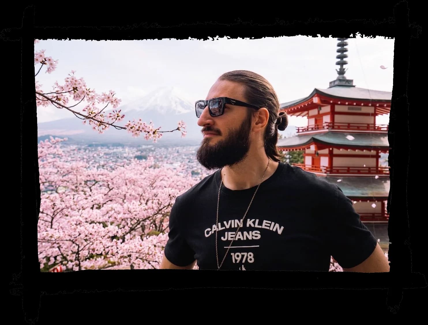 Portrait de Thibault Abraham devant une pagode japonaise, entouré de cerisiers en fleurs